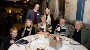 Jenny Price sitting with family and friends around a table at the MSU Denver Scholarship Dinner in the Tivoli Turnhalle